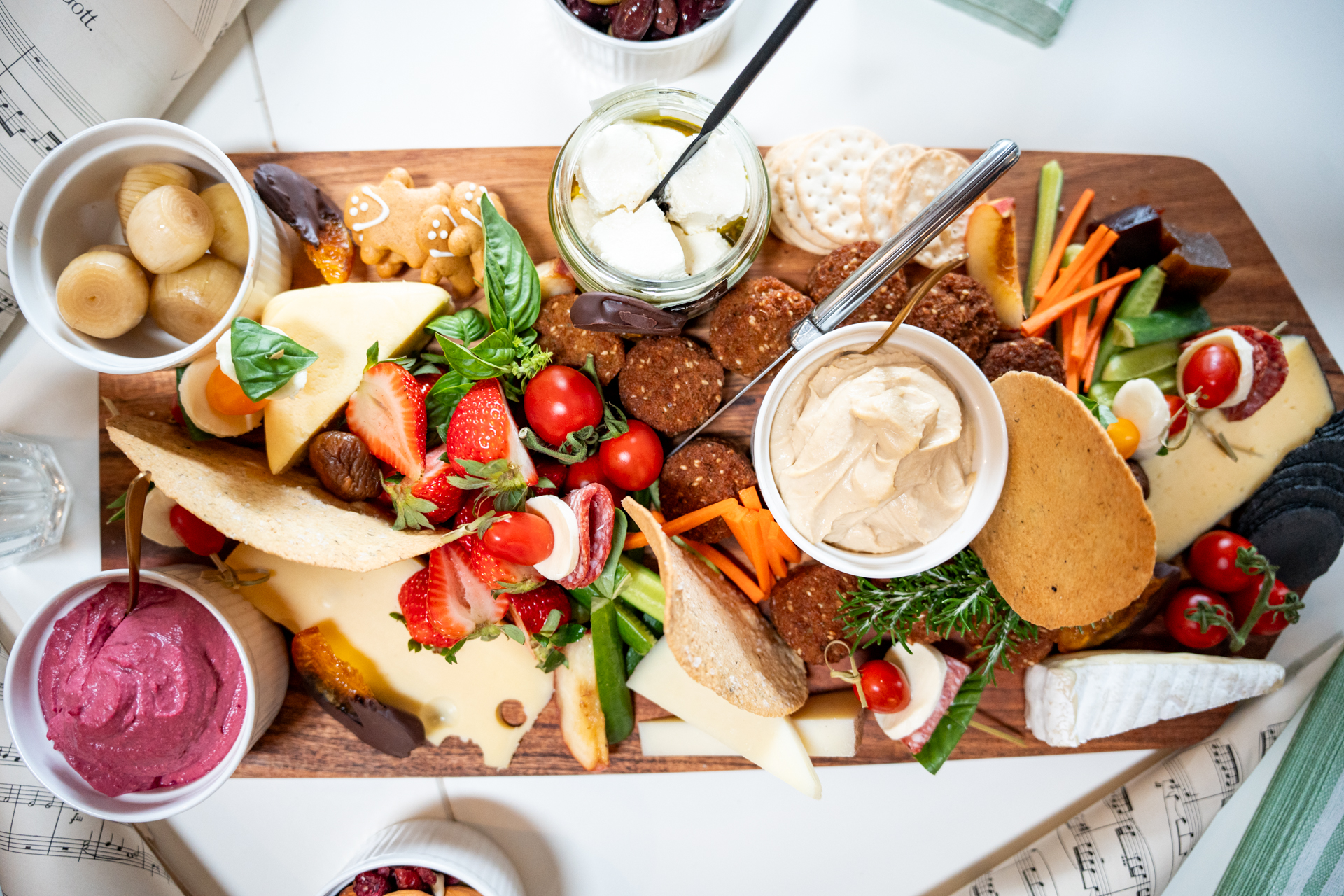 An overhead grazing board with cheeses, dips, crackers and strawberries